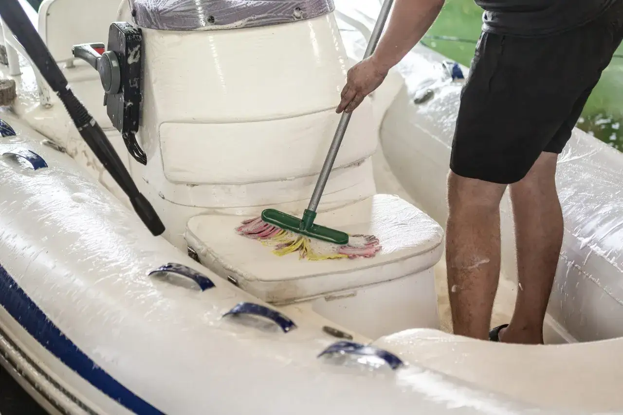 Schlauchbootpflege mit Hausmitteln: Ein Mann reinigt das Boot mit einem Mopp.