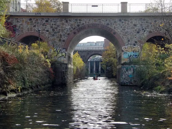 Kanus auf dem Fluss unter einer Steinbrücke mit Graffiti. Sup Leipzig!