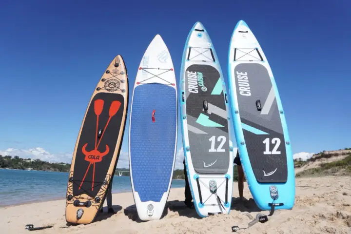Vier aufrecht stehende Standup Boards am Strand, bereit für das Wasser.